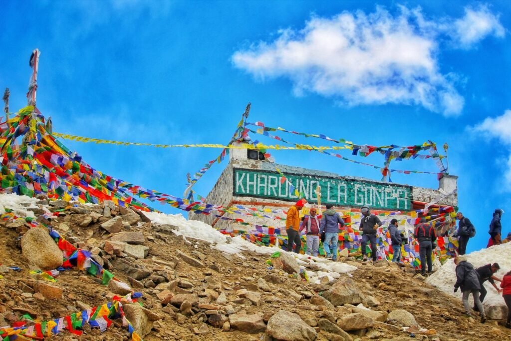 Vibrant scene of Khardung La Pass with people and prayer flags in Ladakh, India.