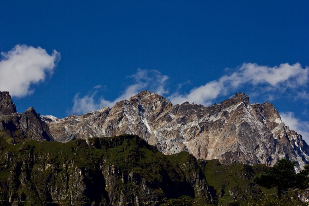 Scenic view of the rugged mountain range in Thangu Valley, illuminated by bright sunlight against a clear blue sky.